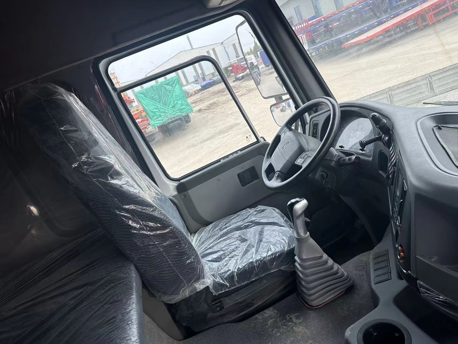 Supplier-provided HOWO cab interior showing the driver's seat, steering wheel and gear lever
