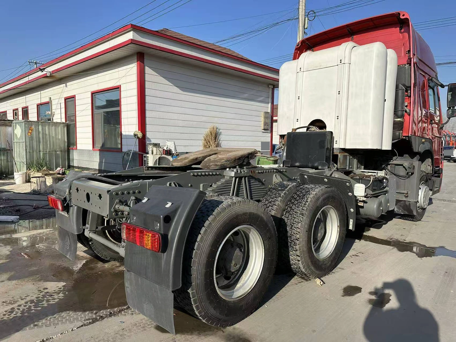 Supplier-provided rear three-quarter view of a red HOWO tractor truck showing the chassis and fifth wheel