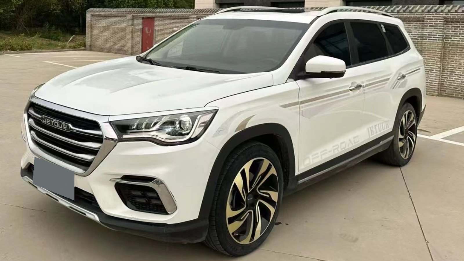 White 2019 Jetour X90 in a front three-quarter view, parked outside a building