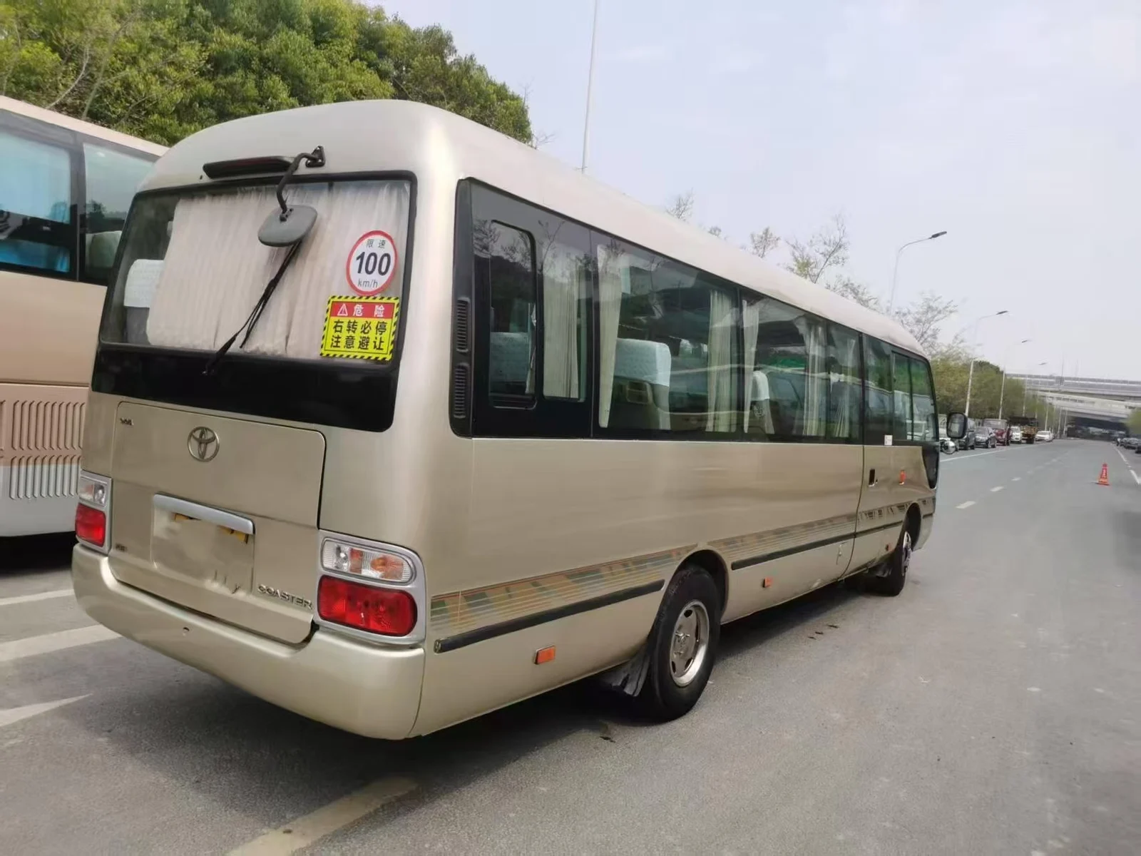 Rear three-quarter exterior view of a used Coaster-style bus during supplier assessment